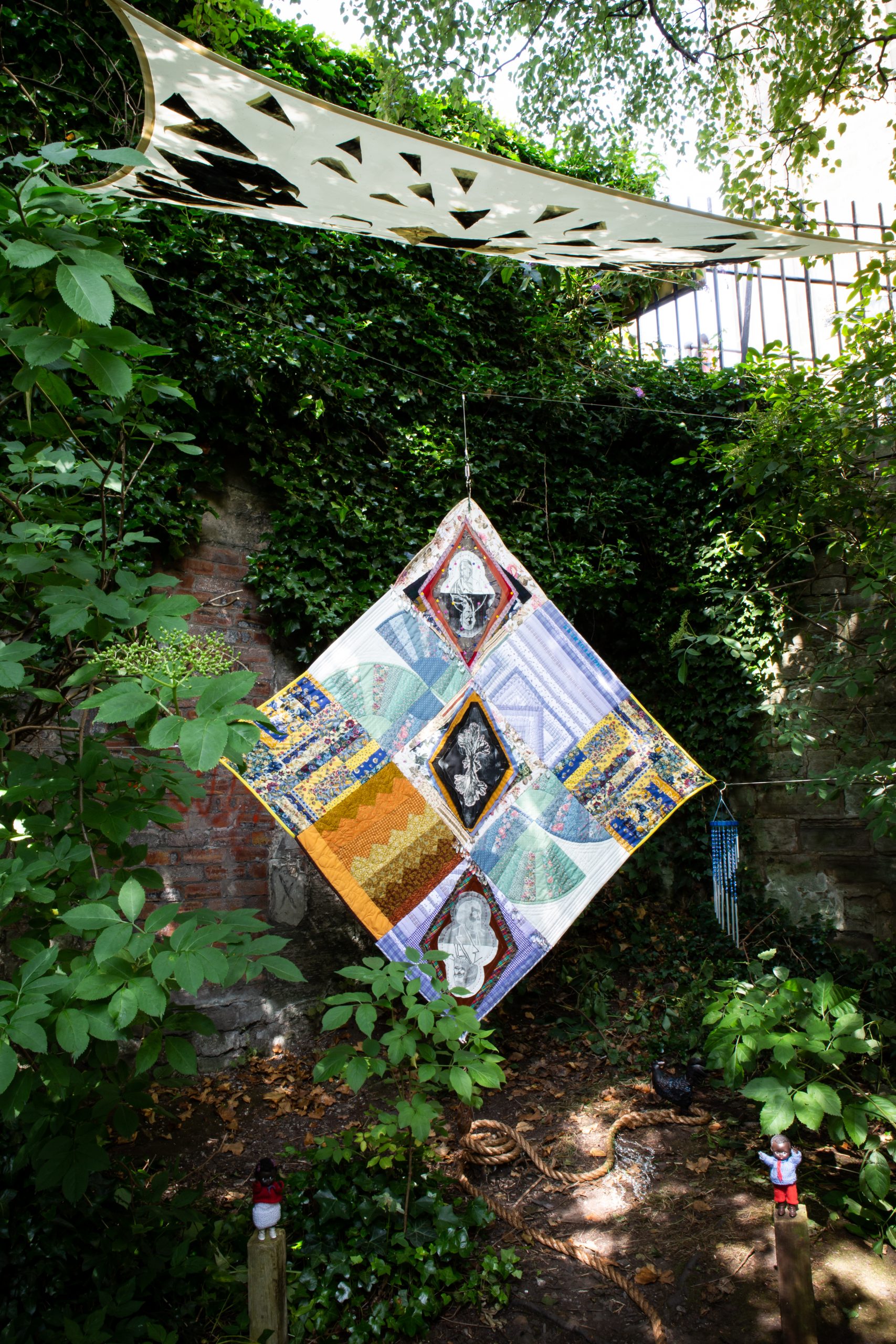 Textile installation set against garden wall.