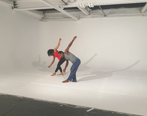 Ashanti Harris and dancer perform against white studio backdrop.