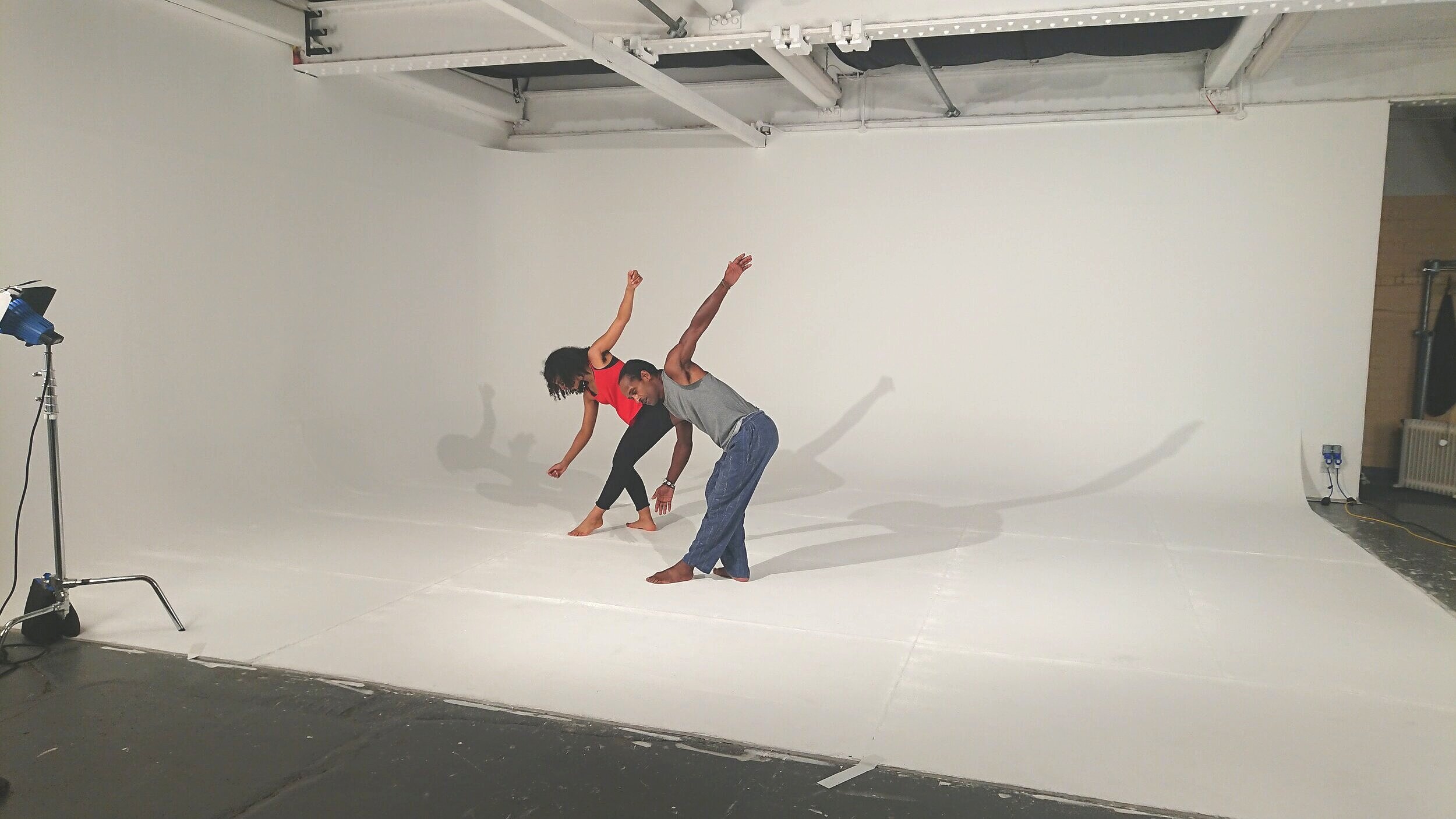 Ashanti Harris and dancer perform against white studio backdrop.