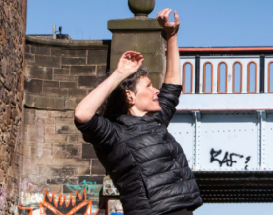 Janice Parker stands on canal with hands in the air.