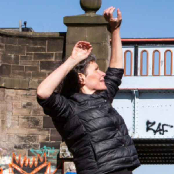 Janice Parker stands on canal with hands in the air.