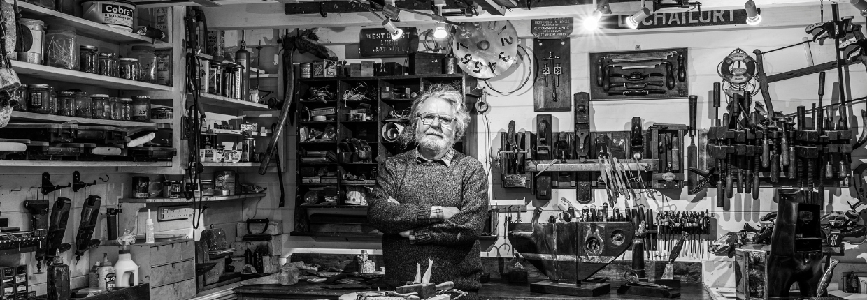 Black and white image of Will Maclean standing in his studio.