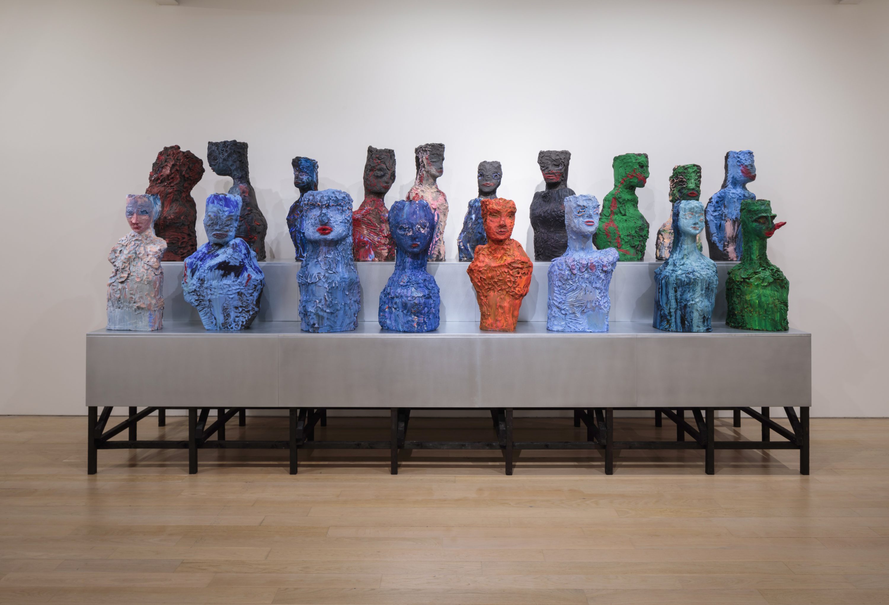 A number of heads in colourful clay line metal table.