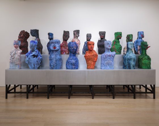 A number of heads in colourful clay line metal table.